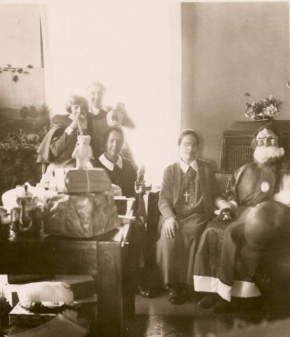 Anna Dengel sits next to Sister Alma who is dressed up as Santa, 1930